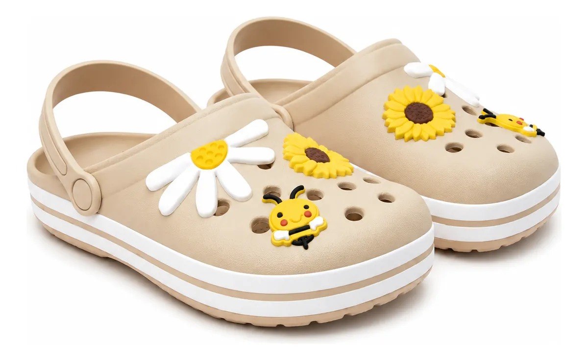 Par de babuches infantis na cor bege com solado branco, decorados com apliques de flores brancas, uma flor amarela e uma abelha sorridente.